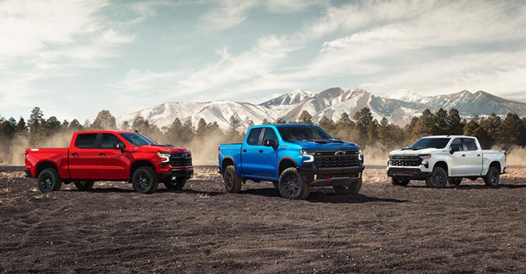 2026 Chevrolet Silverado Three pickup trucks parked on rugged terrain.