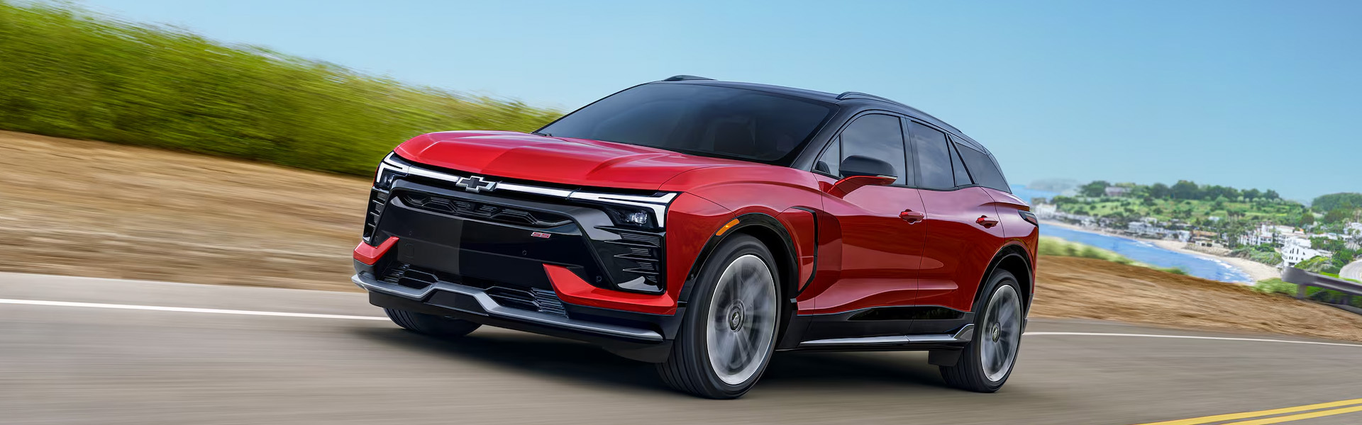 2026 Chevy Blazer EV electric SUV driving on a scenic coastal highway.
